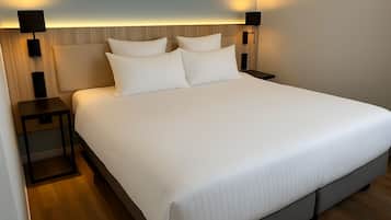 A large bed with a wooden headboard, two bedside tables, and two wall-mounted lamps.