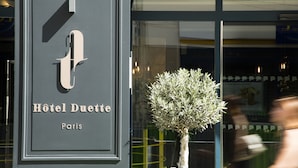 Cartell de l'Hôtel Duette a París, amb un disseny minimalista i una petita planta en test amb vistes a l'entrada.