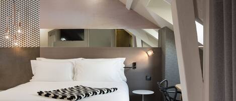 Une chambre d’hôtel moderne avec un lit, une petite table ronde et une chaise.