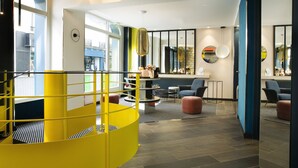 Un interior modern amb una escala espirala groga, una zona d'estar amb seients i una taula, i un mirall gran a la paret.