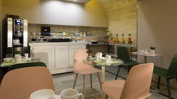 A modern kitchen with a coffee machine, breakfast bar, and seating area with chairs and a table.