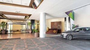 A hotel lobby with a reception desk, a car parked outside, and potted plants. - Guadalajara Plaza Expo Business Class (Guadalajara)