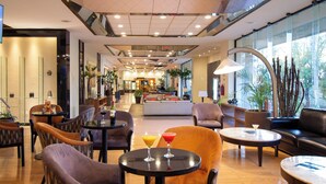 A spacious lobby with multiple seating areas, including sofas and chairs, and a central area with a reception desk. - Guadalajara Plaza Expo Business Class (Guadalajara)