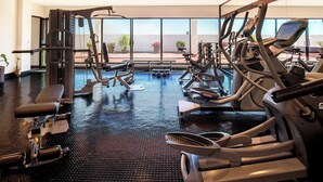 A gym with various exercise machines, a large window, and a view of the outdoors. - Guadalajara Plaza Expo Business Class (Guadalajara)