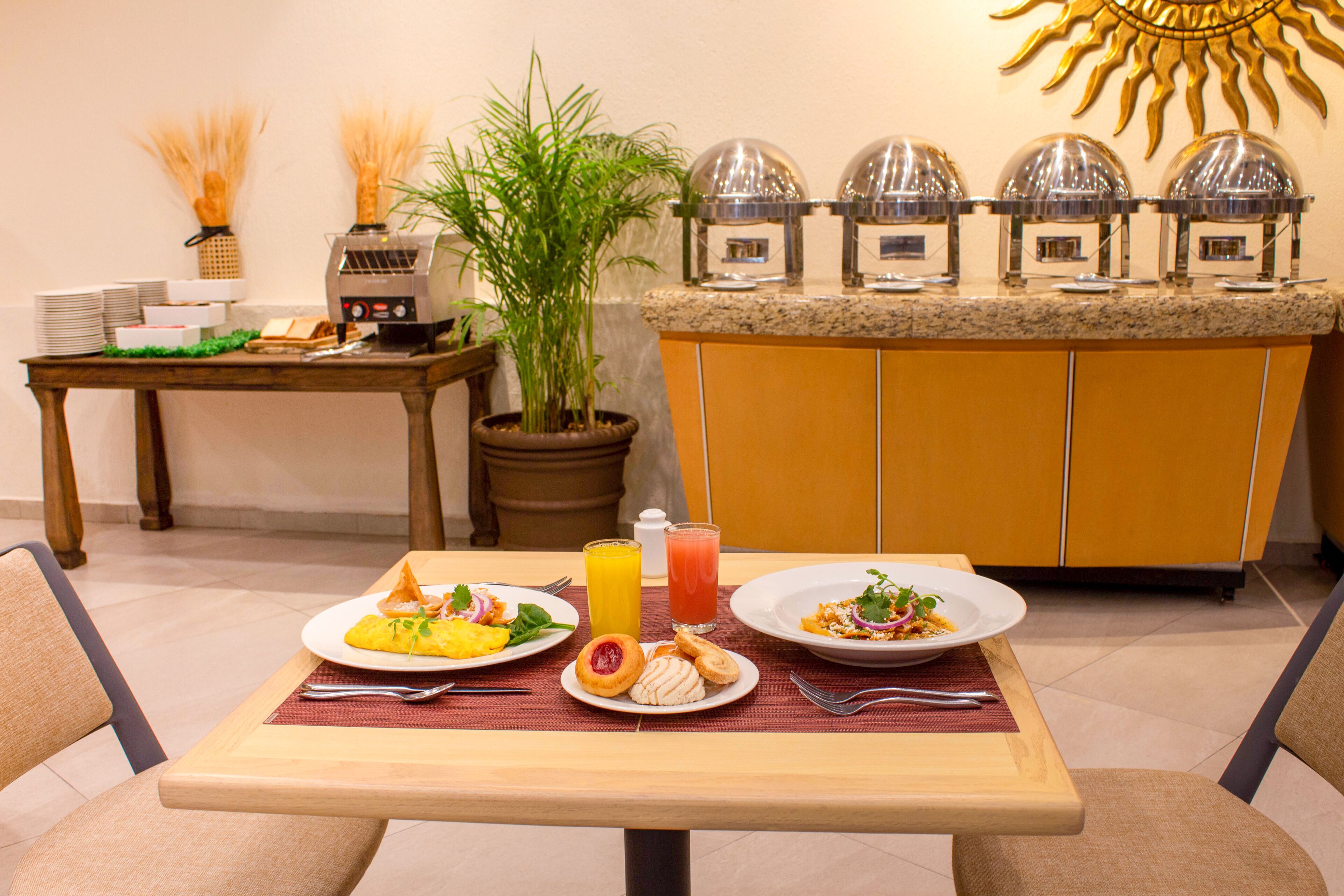 A breakfast table with plates of food, a fruit bowl, and a juice glass.