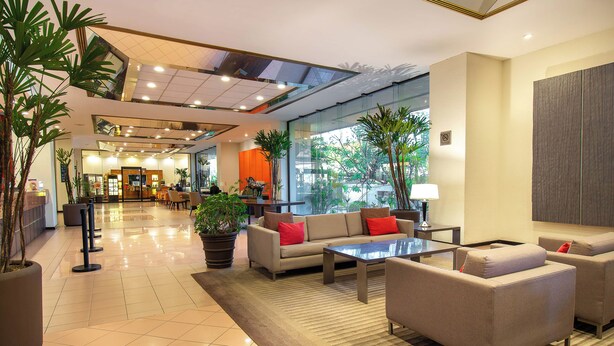 A spacious lobby with a sofa set, a coffee table, and potted plants. - Guadalajara Plaza Expo Business Class (Guadalajara)