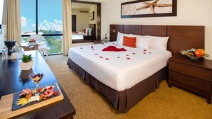 A hotel room with a large bed, a dining table with a fruit platter, a nightstand with a fruit bowl, and a balcony with a view. - Guadalajara Plaza Expo Business Class (Guadalajara)