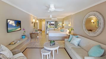 A spacious living room with a sofa, a dining table, and a TV mounted on the wall.