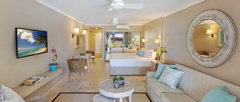 A spacious living room with a sofa, a dining table, and a TV mounted on the wall.