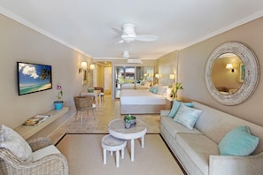A spacious living room with a sofa, a dining table, and a TV mounted on the wall.