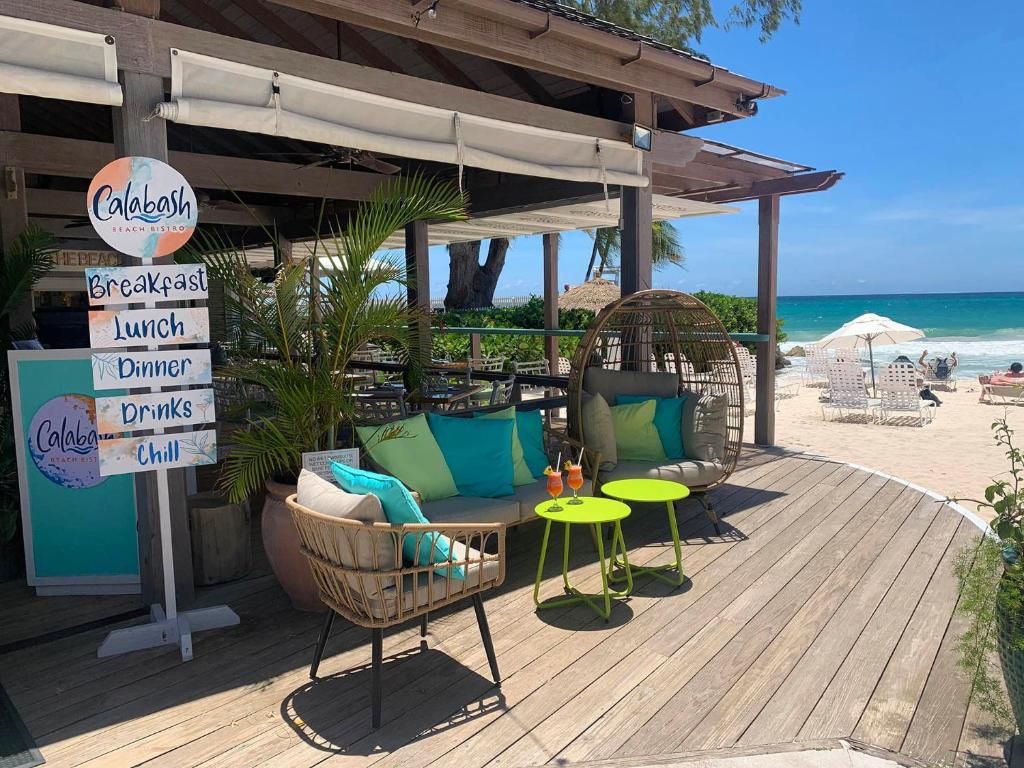 Um restaurante à beira-mar com área externa, incluindo uma cadeira de vime e uma mesa redonda, e um letreiro com opções de refeições.