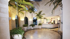A lobby with a circular tiled floor, potted plants, and a reception desk. - Bougainvillea Barbados (Maxwell)