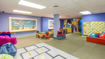 A children's playroom with colorful furniture, educational posters, and a large window.