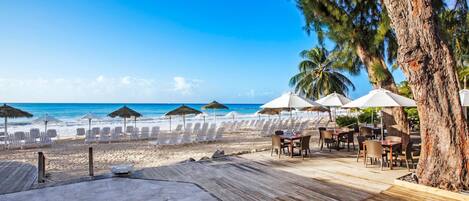 A beachside restaurant with outdoor seating, overlooking the ocean.