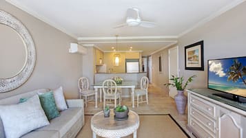 Una sala de estar con un sofá, una mesa de centro, un televisor y un comedor con sillas y una mesa.