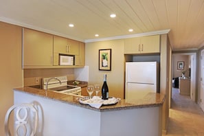 A compact kitchen with a microwave, a wine bottle, and two glasses on the counter.