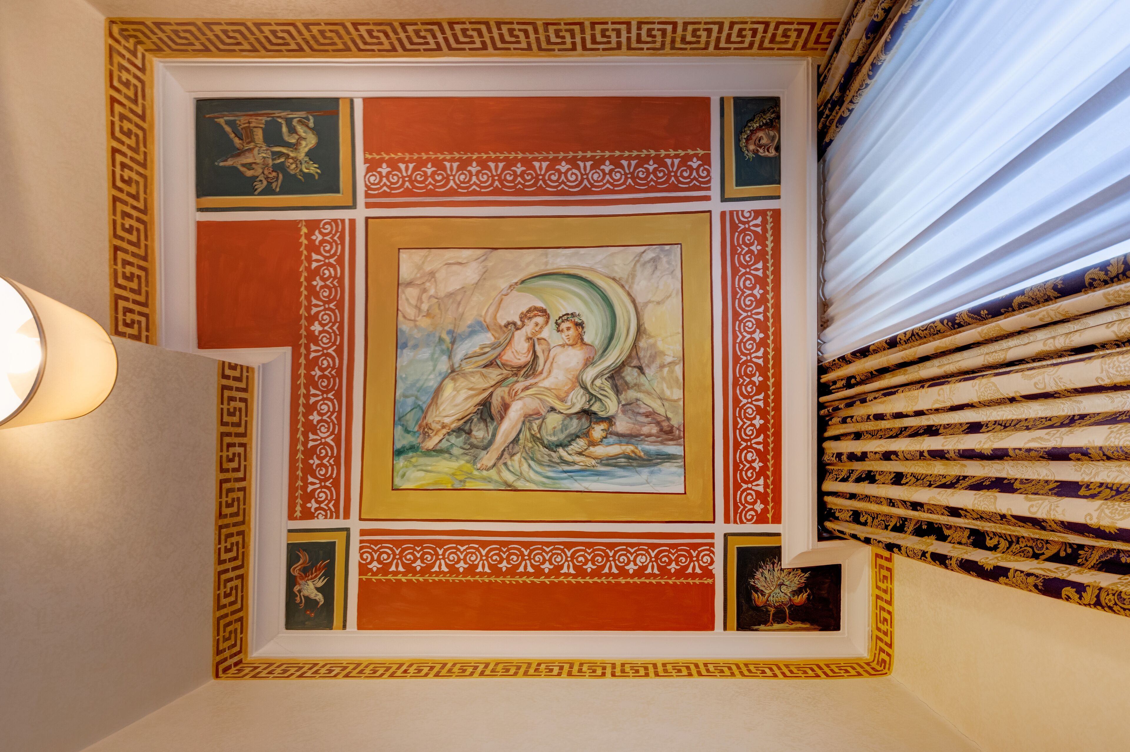 A ceiling with classical artwork and decorative patterns.