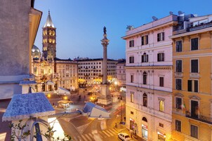 A historic square with a prominent monument, classical architecture, and a clock tower.