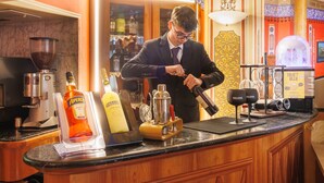 Un coin bar où un barman prépare un cocktail, avec une bouteille d’Aperol, une bouteille de Gallinette et un robinet de bière Bulldog.