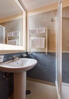 A bathroom with a sink, mirror, towel rack, and shower area.