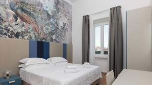 Une chambre d’hôtel comprenant un lit, un bureau, une table de chevet et une grande fresque murale.