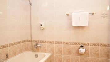 A bathroom with a bathtub, a showerhead, a towel rack with a towel, and a toilet paper holder.