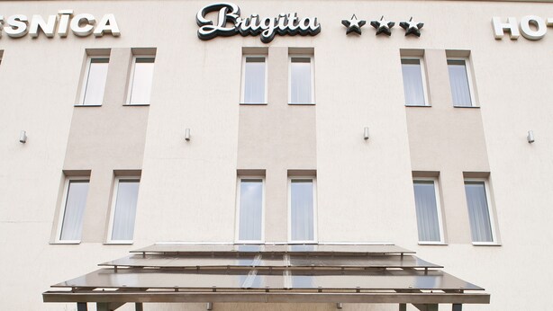 A hotel entrance with a staircase, a covered walkway, and signage for the hotel and its amenities.