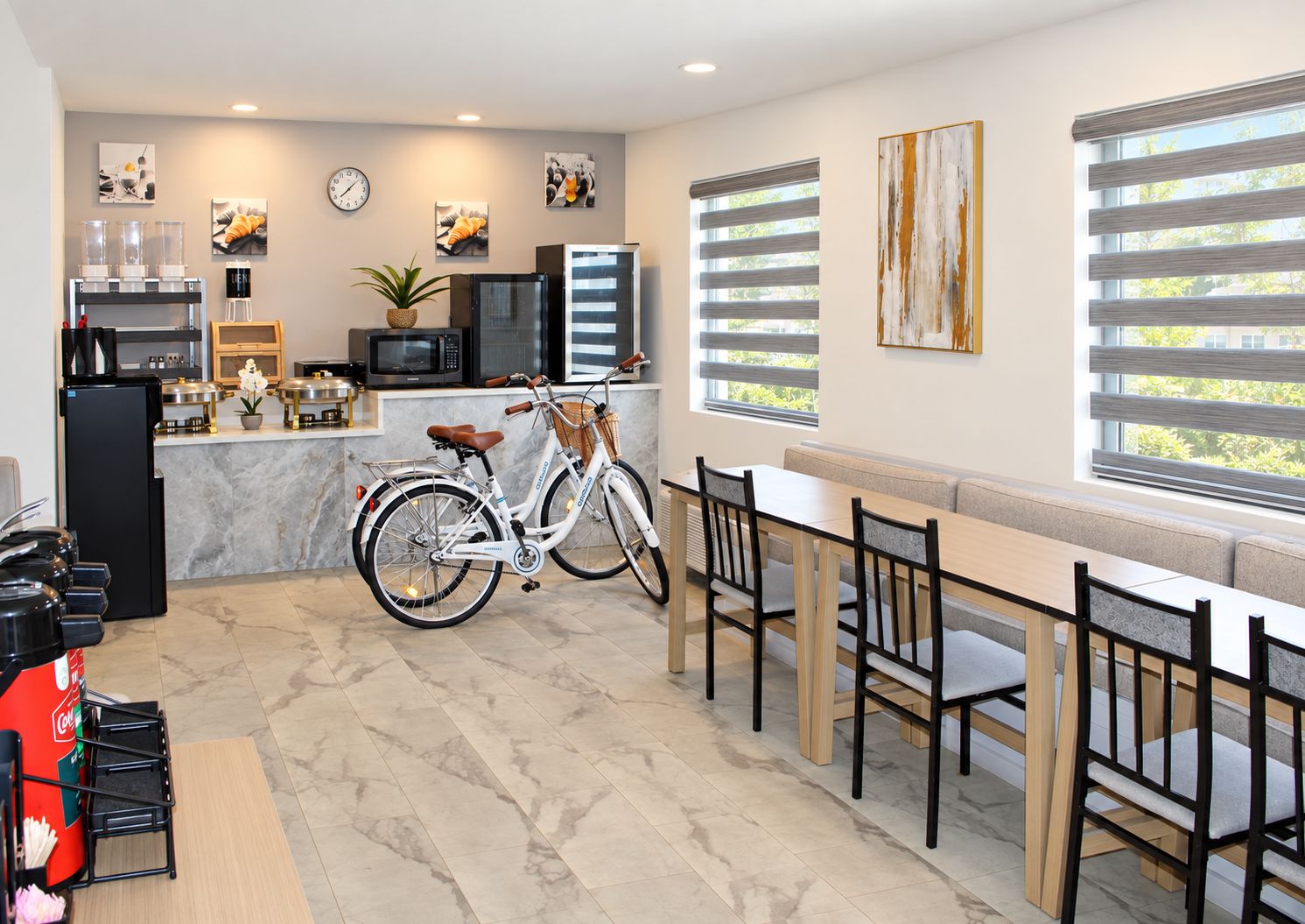 A modern kitchen with a bicycle, dining area with chairs, and artwork on the walls.
