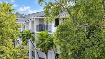 A multi-story building with balconies, surrounded by lush greenery.