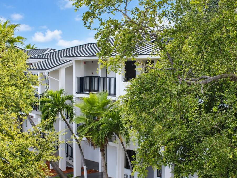 A multi-story building with balconies, surrounded by lush greenery.
