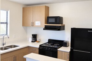 Una cocina moderna con armarios de madera, estufa negra, microondas y refrigerador.