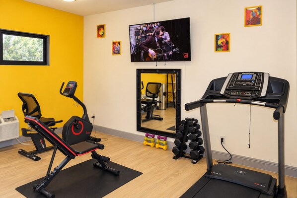 Un gimnasio con equipo cardiovascular, un espejo grande y pelotas de ejercicio.