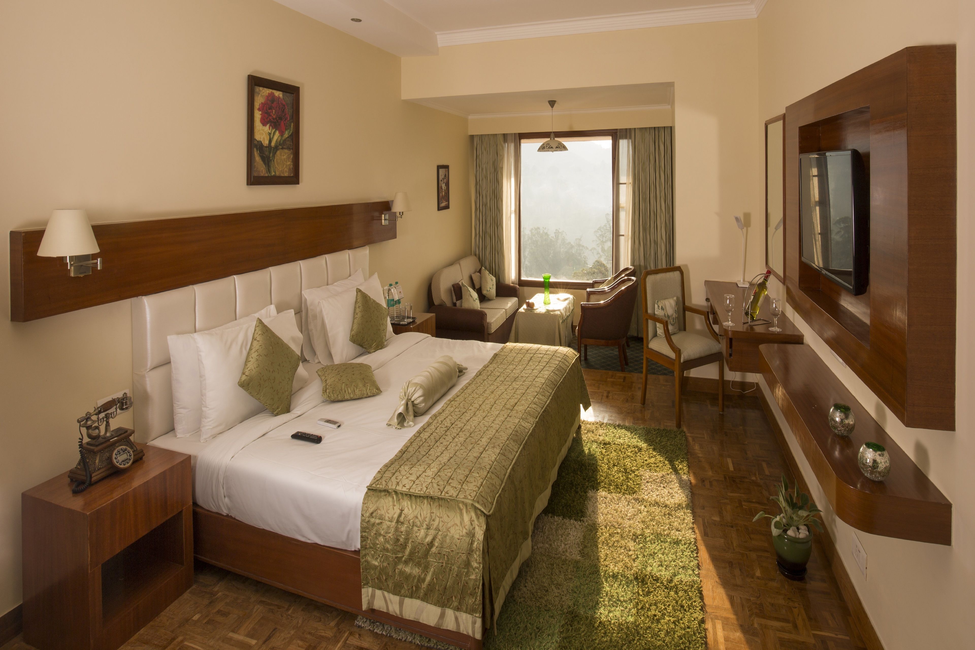 Habitación de hotel con una cama grande, un escritorio, una silla, un televisor y una ventana con cortinas.