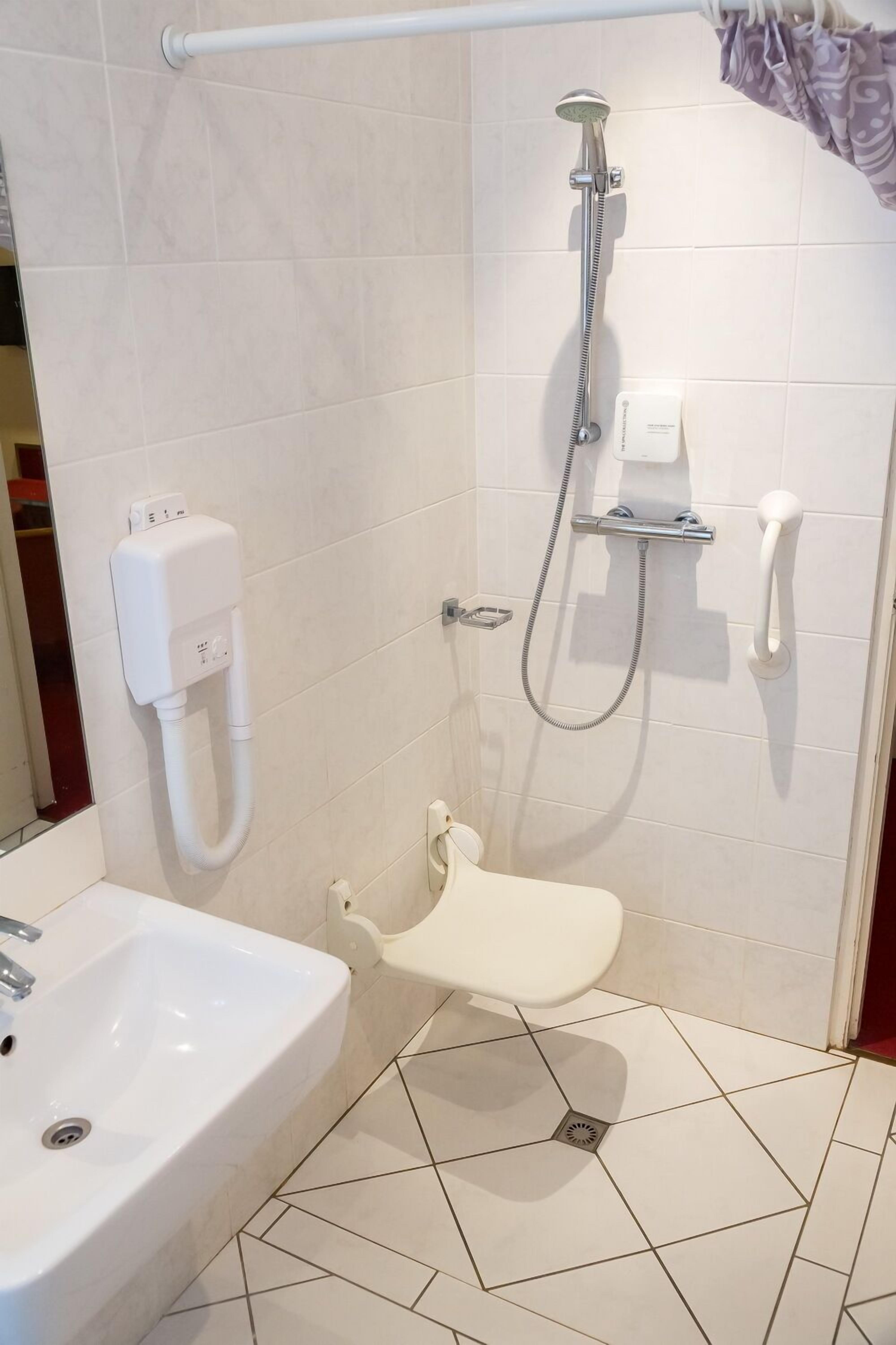Een badkamer met douche, toilet en wastafel.