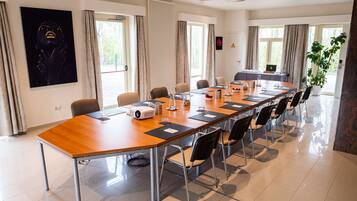 A conference room with a long table, chairs, a projector, and a potted plant.