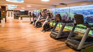 Een sportschool met meerdere loopbanden langs een muur met een mooi uitzicht.