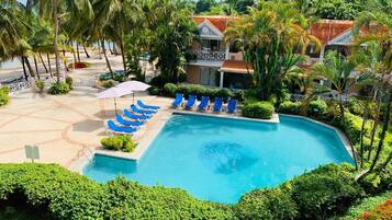 Una piscina al aire libre, sombrillas, sillones reclinables de piscina