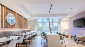 Un moderno comedor con una isla central, diversas opciones de asientos y grandes ventanales que aportan luz natural.