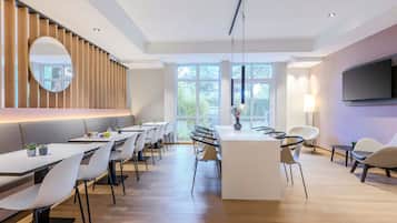 Un espace de repas moderne doté d’un îlot central, de plusieurs configurations de sièges et de grandes fenêtres qui laissent entrer la lumière naturelle.