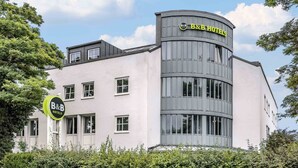 Un hotel B&B con diseño moderno, que destaca por su fachada curva y múltiples ventanas.
