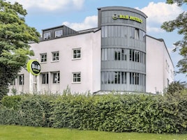 Un hotel B&B con diseño moderno, que destaca por su fachada curva y múltiples ventanas.