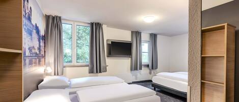 A hotel room with two beds, a TV mounted on the wall, and a window with curtains.