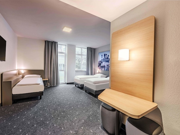 A hotel room with a bed, a desk, and a large window.