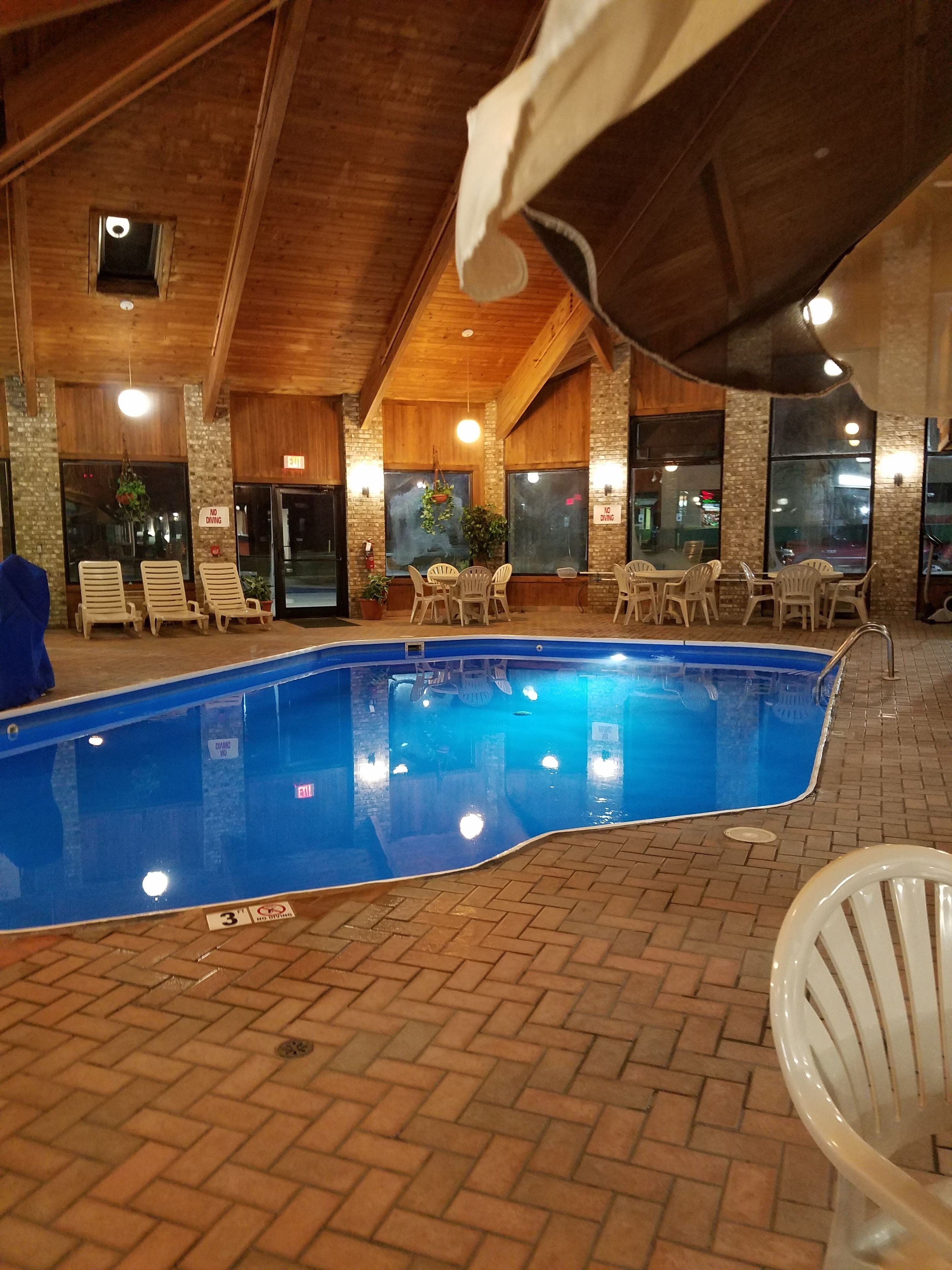 Una piscina interior con suelo de ladrillo, rodeada de sillones y mesas.