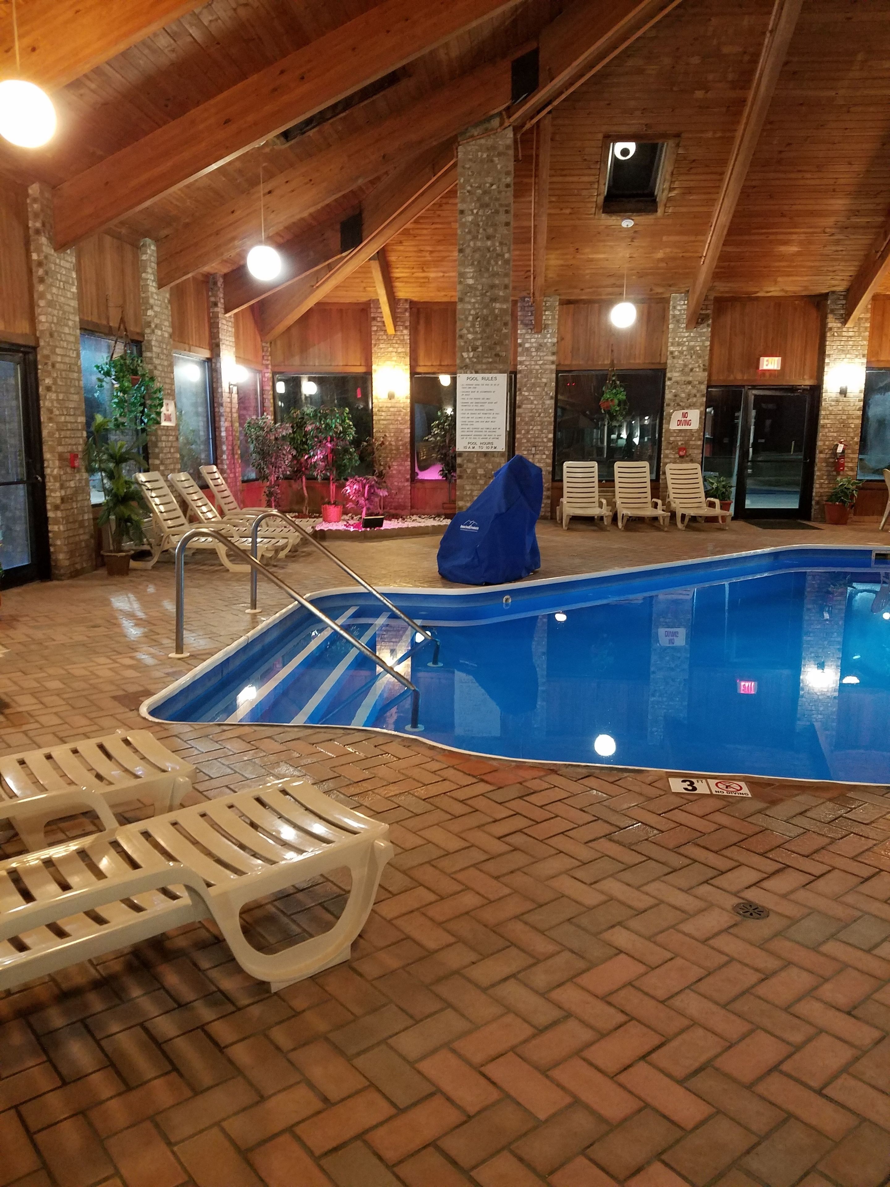 Una piscina interior con sillones de descanso y suelo de ladrillo.