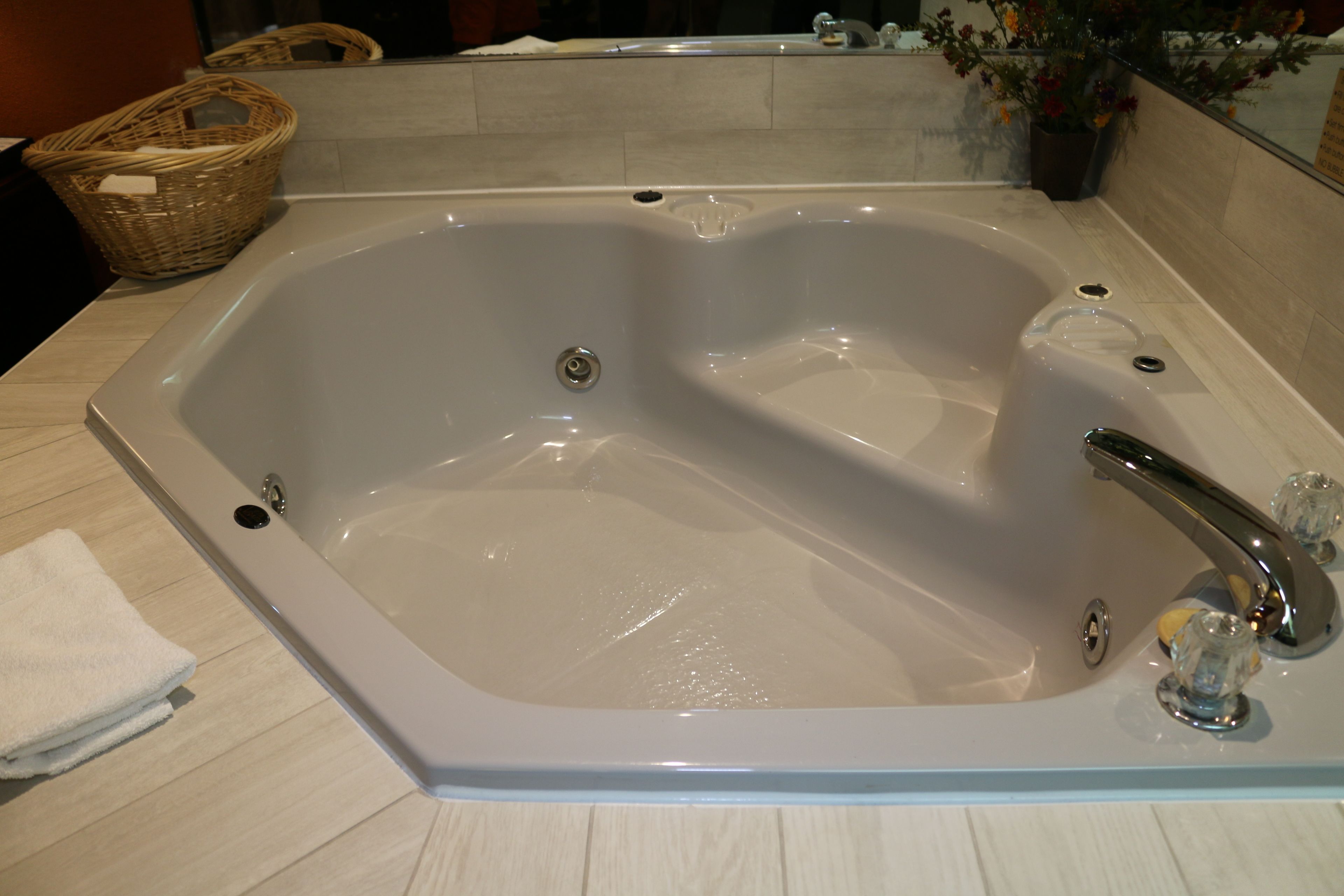 A large, rectangular bathtub with a single faucet and a drain.