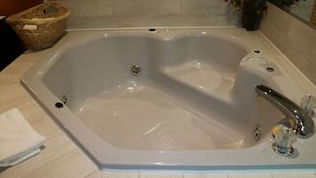 A large, rectangular bathtub with a single faucet and a drain.