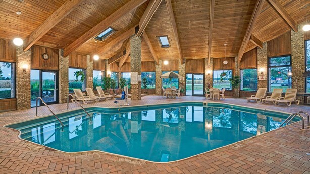 Una piscina interior con vigas de madera, pilares de piedra y suelo de ladrillo.