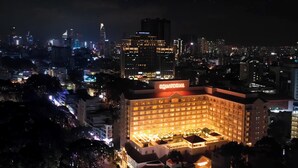 A hotel with a prominent 'Equatorial' sign, surrounded by a cityscape at night. - Equatorial Ho Chi Minh City (Ho Chi Minh City)