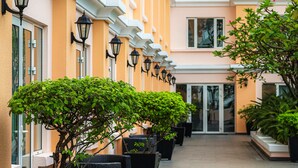 A row of hotel rooms with balconies, potted plants, and outdoor lighting. - Equatorial Ho Chi Minh City (Ho Chi Minh City)